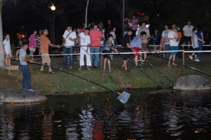 年轻人在湖畔旁参与捞柑活动。