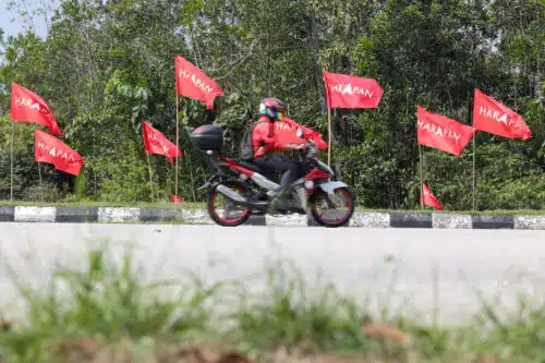 Seorang penunggang motosikal melintas bahu jalan yang dihiasi dengan bendera Pakatan Harapan ketika tinjauan di sekitar Kerling, Hulu Selangor pada 29 April 2024. Foto FIKRI YUSOF/SELANGORKINI